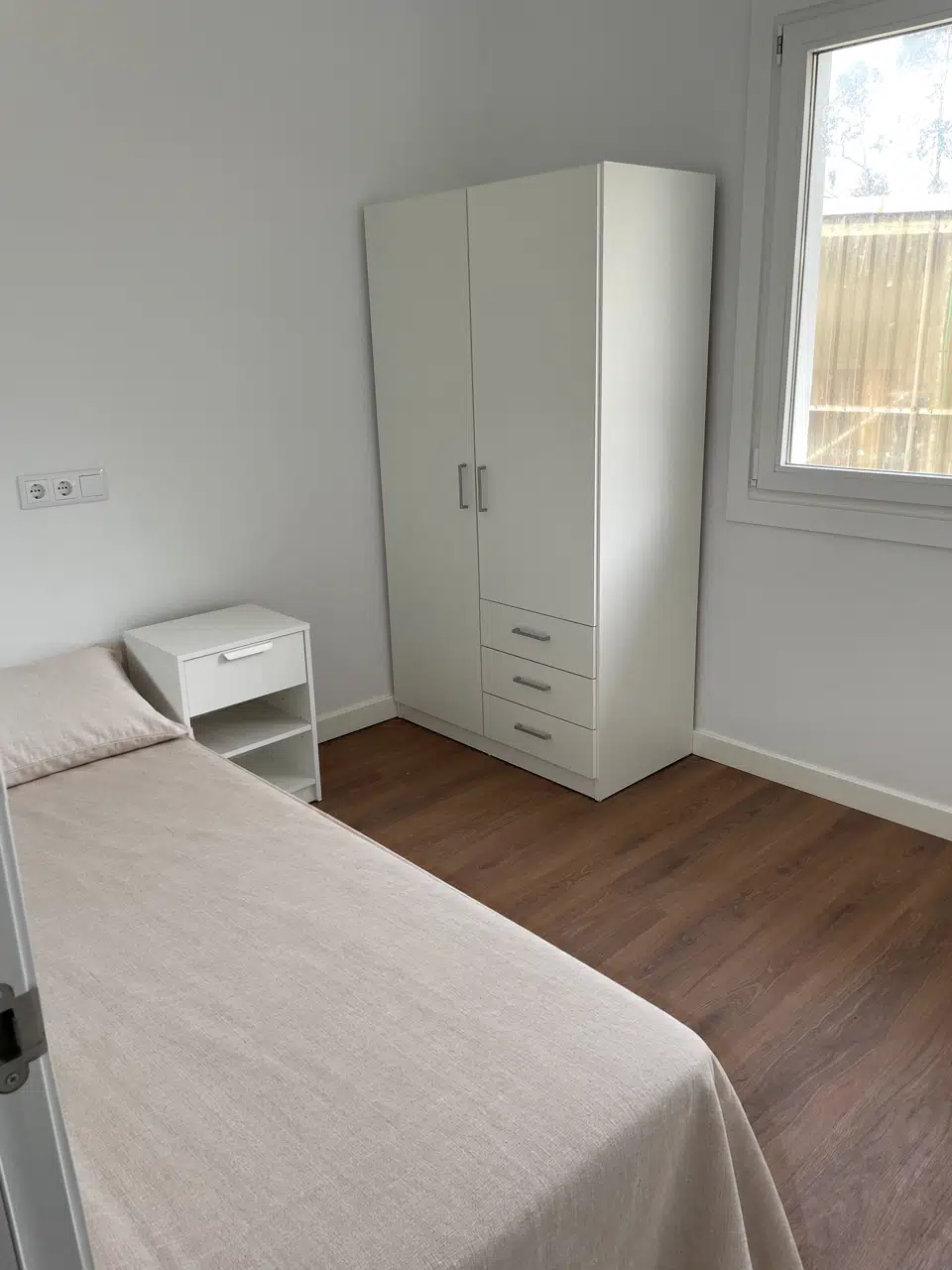 Primer dormitorio individual con cama, mesilla y armario blancos