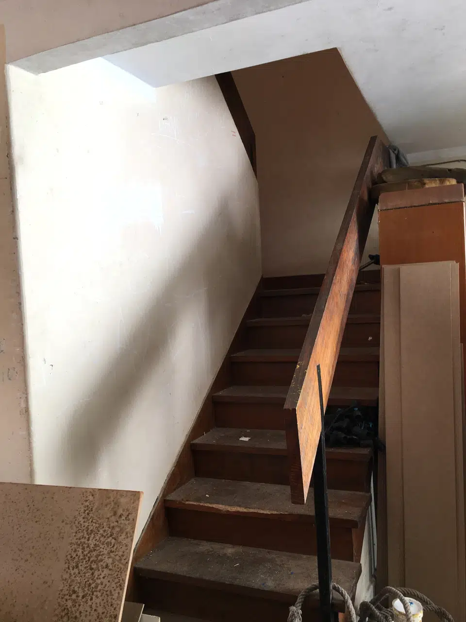 Escalera de madera antes de su restauración, con materiales almacenados