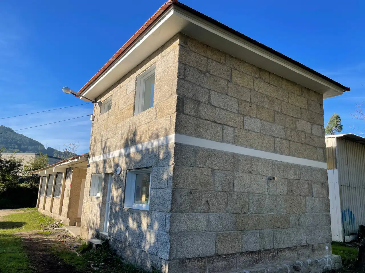 Fachada de piedra rehabilitada · Vivienda del maestro en A Sequiña