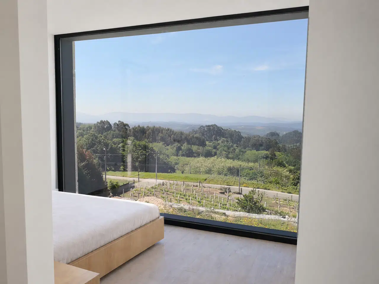 Dormitorio vacío con un gran ventanal enmarcando el paisaje