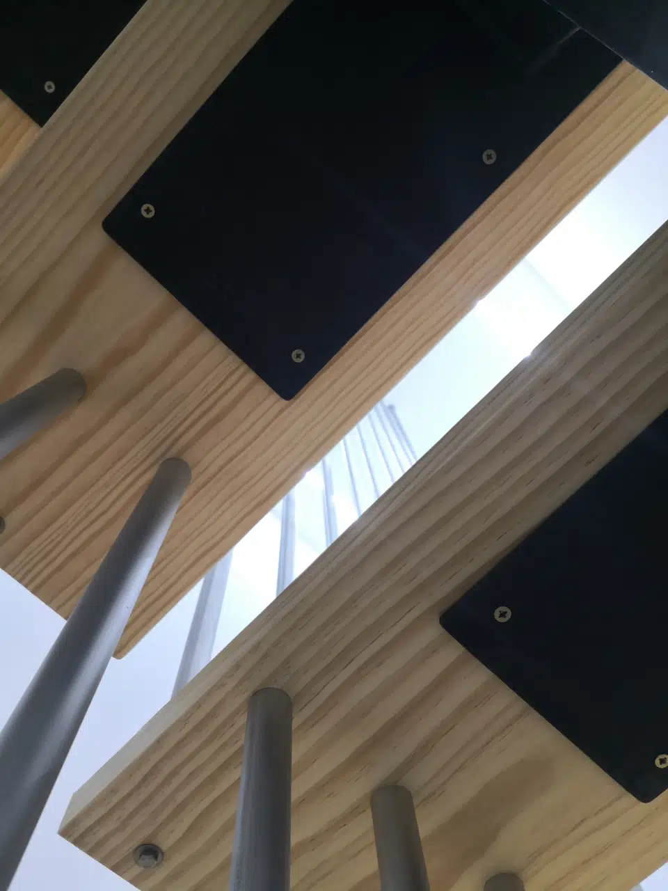 Detalle inferior de los peldaños de madera y sus uniones con la estructura de acero